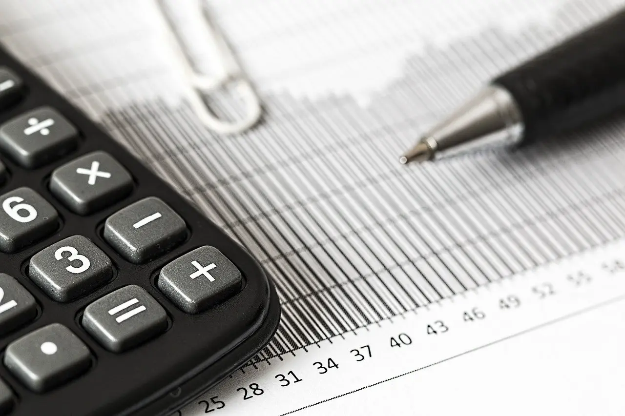 Imagem mostra uma calcularadora, papel e caneta