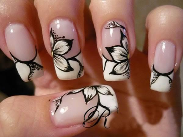 Unhas da mão com flores brancas e contorno preto