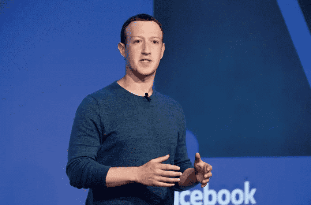 Foto mostra o milionário Mark Zuckerberg, homem branco, usando um suéter azul, em fundo azul.