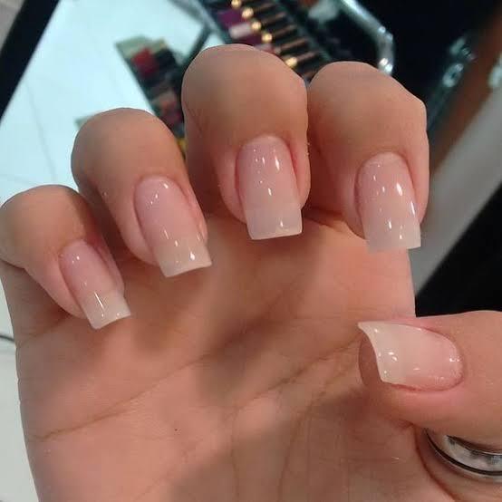 Unhas da mão quadradas e com um esmalte claro e transparente