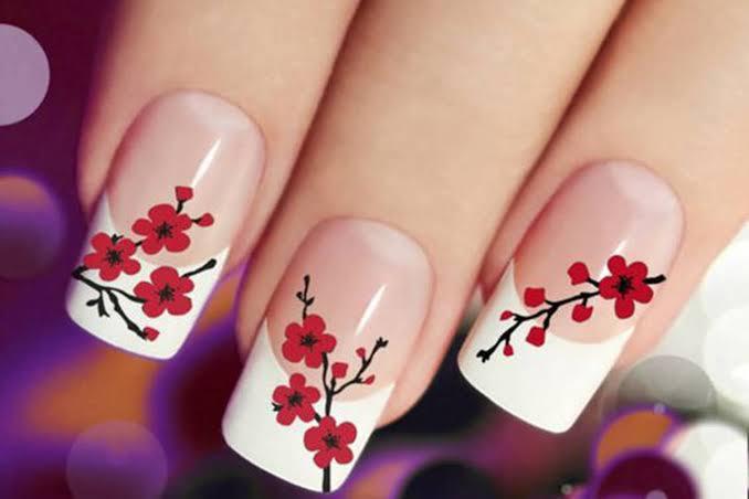 Unhas da mão com flores vermelhas e francesinha branca