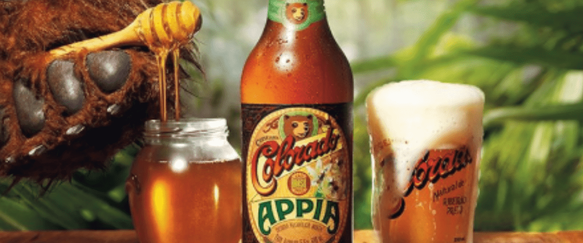 Garrafa de Colorado Appia ao lado de copo e jarro de mel - marcas de cerveja artesanal 
