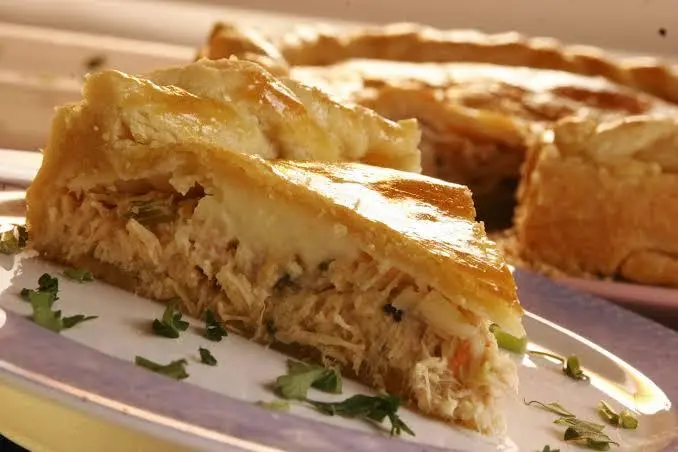 receitas de frango - Á frente um pedaço de torta de frango em um prato branco e ao fundo o resto da torta