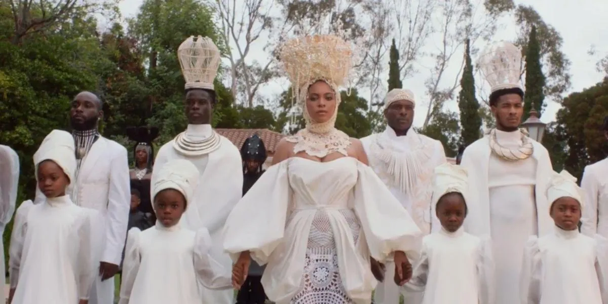 Beyoncé de branco rodeada de pessoas em cena do clipe do filme Black is King