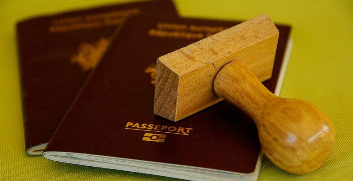 dois passaportes vermelhos, um sobre o outro, com um carimbo de madeira