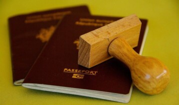 dois passaportes vermelhos, um sobre o outro, com um carimbo de madeira