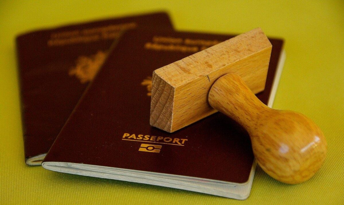 dois passaportes vermelhos, um sobre o outro, com um carimbo de madeira