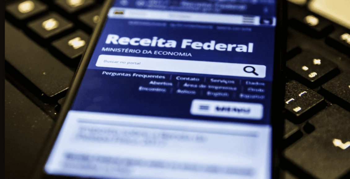 Celular com site da receita federal aberto, em cima de um teclado.