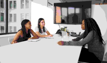 Três mulheres sentadas em torno de uma mesa em um escritório