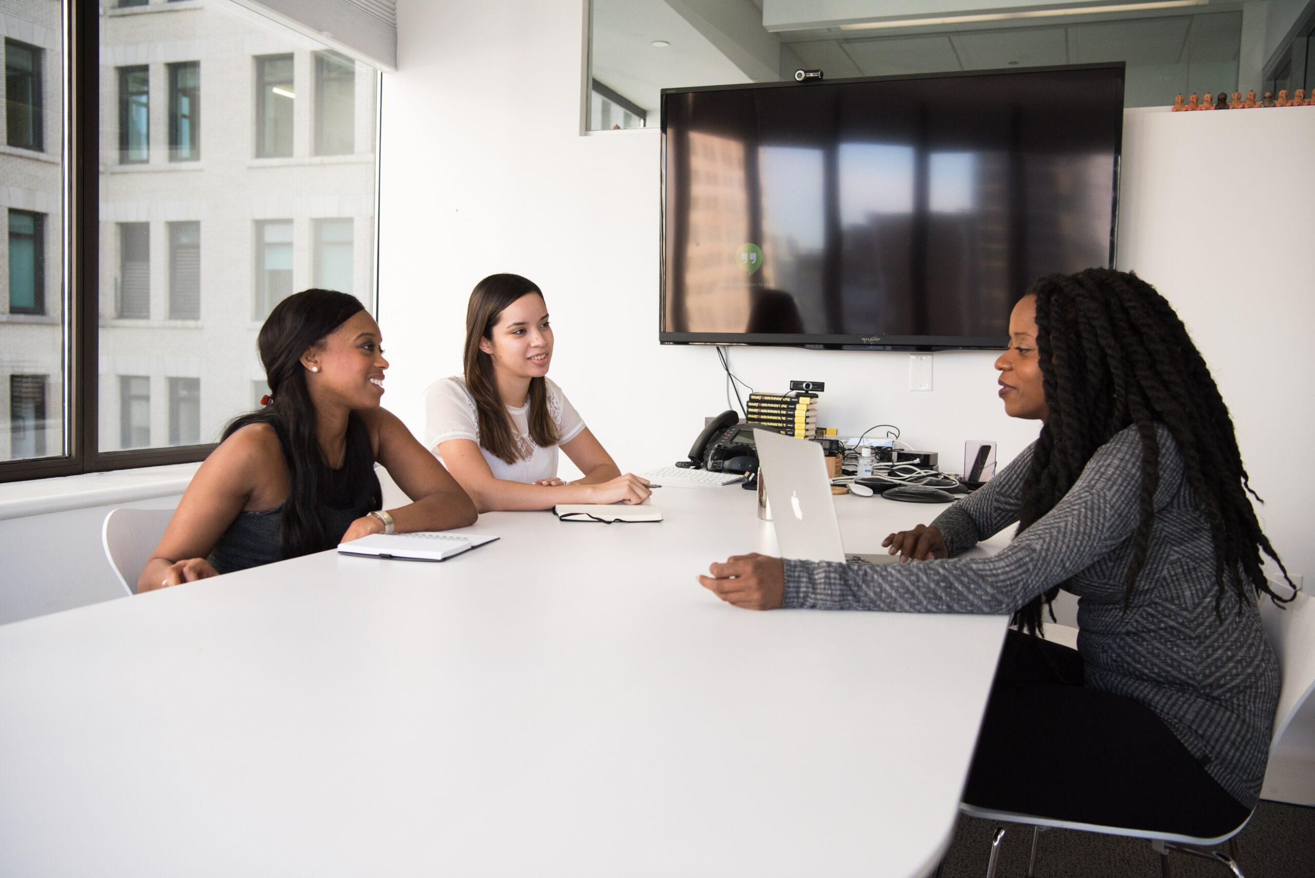 Três mulheres sentadas em torno de uma mesa em um escritório