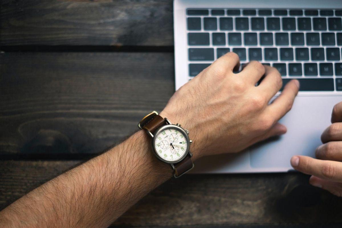 Mão com relógio sobre computador aumentar produtividade como freelancer