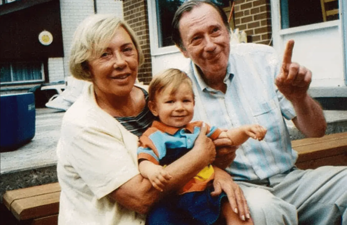 Foto mostra casal de idosos, sentados com uma criança no colo.