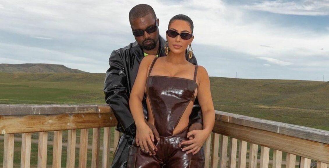 Kim Kardashian e Kanye West posados em um cerca de madeira