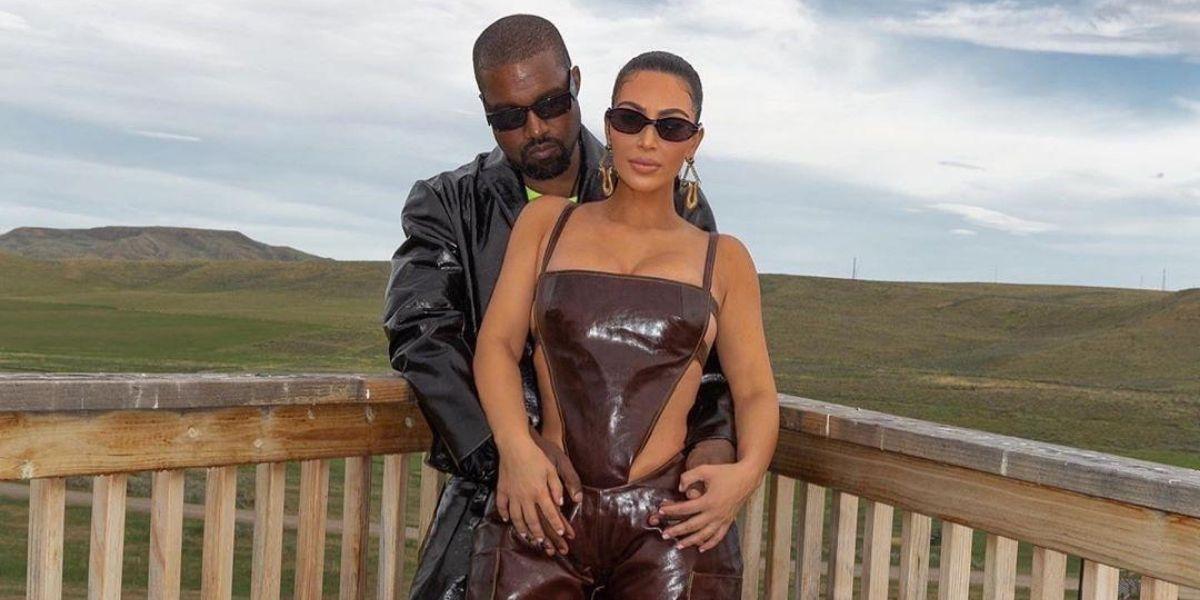 Kim Kardashian e Kanye West posados em um cerca de madeira