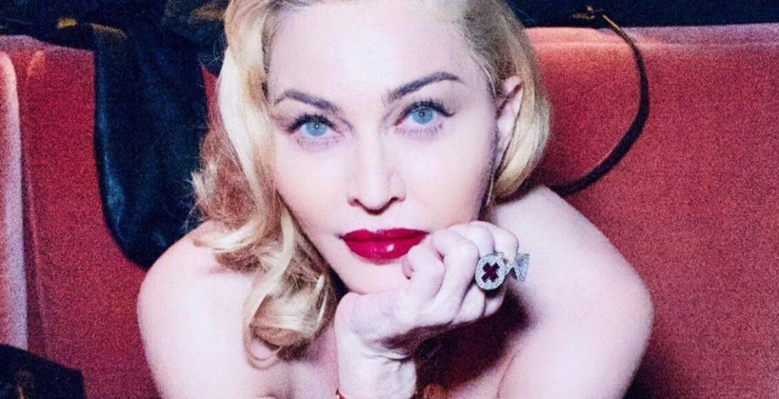 Madonna deitada olhando para frente com a mão no queixo