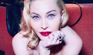 Madonna deitada olhando para frente com a mão no queixo