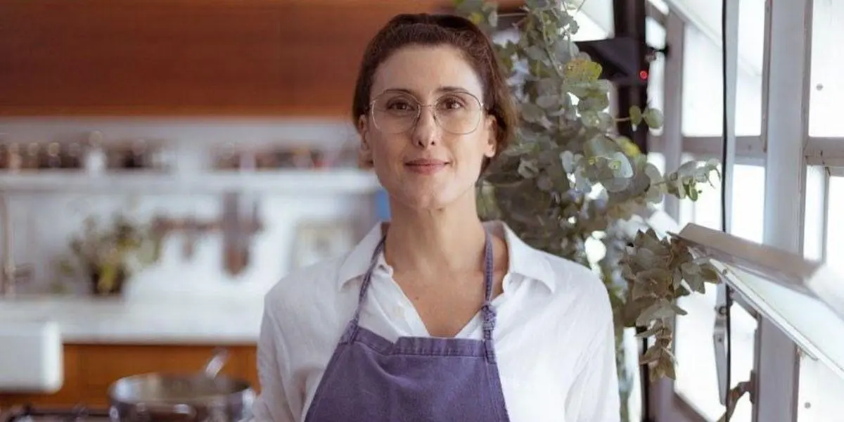 Paola Carosella posada em sua cozinha olhando para frente