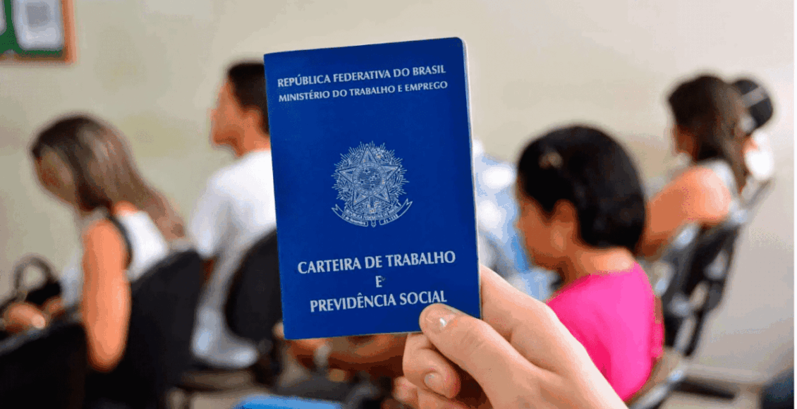 Foto de uma mão segurando uma carteira de trabalho.