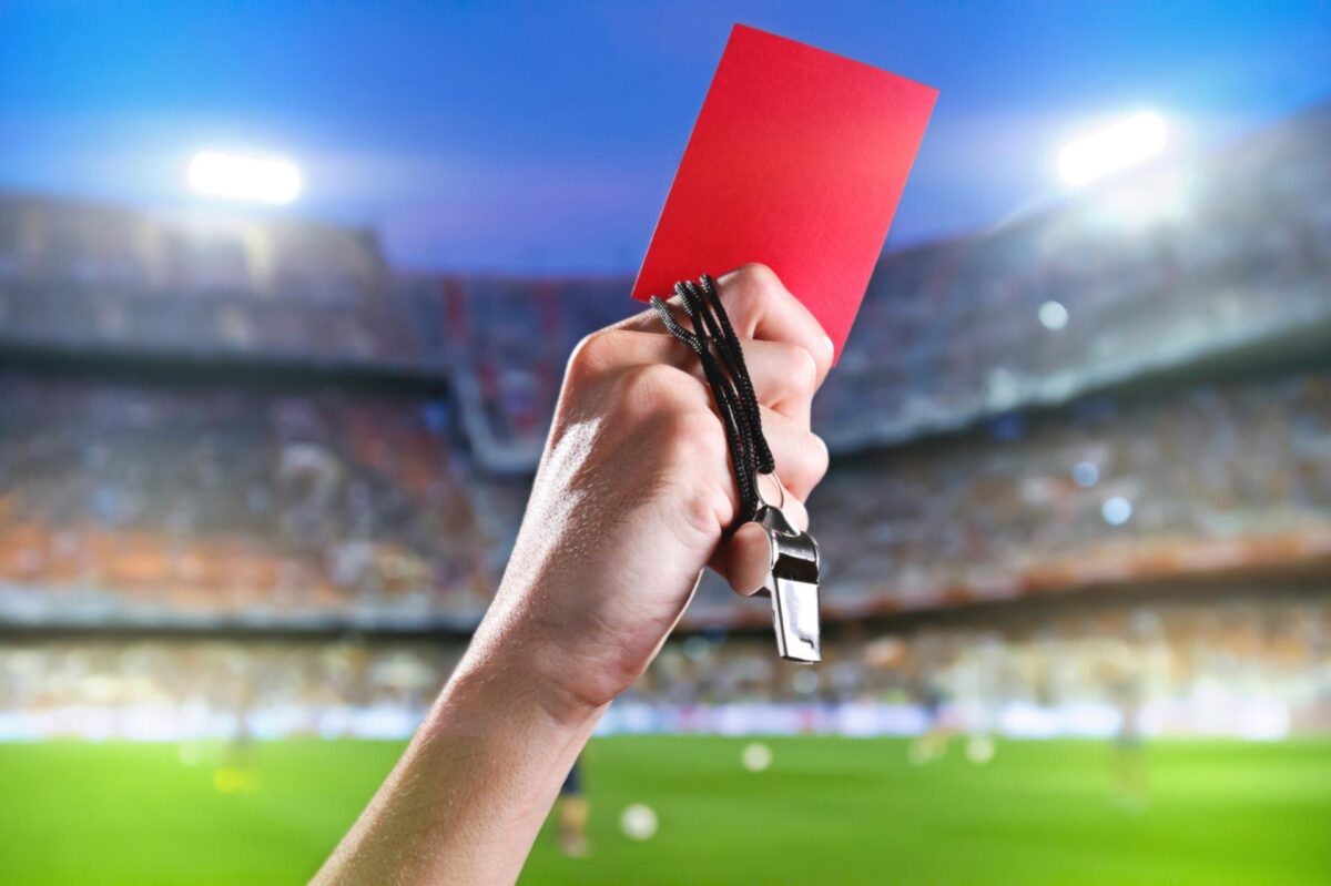 "Pra cego ver": na foto ilustrativa temos um foto não-verbal com um braço com um cartão vermelho à mão para jogadores suspensos