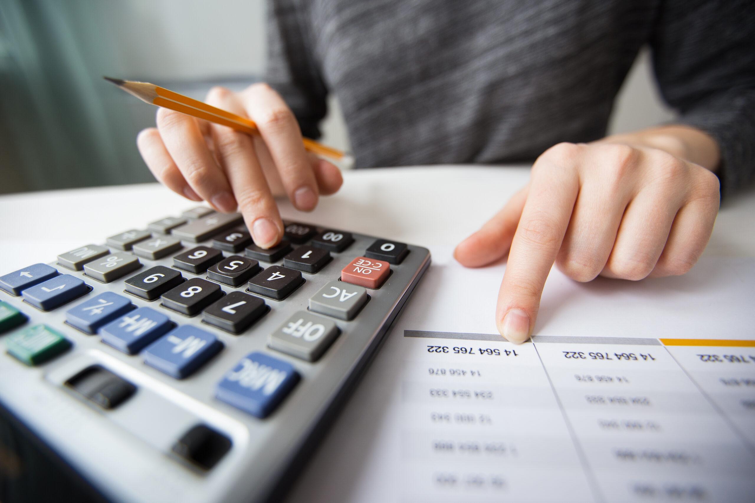 Pessoa com calculadora, lápis e papel
