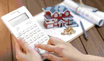 Fundos imobiliários. Pessoa com calculadora e casa de brinquedo ao fundo