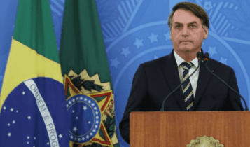 Conheça a lei de negociação de dívidas das micro empresas: Jair Bolsonaro aparece em púlpito à frente de fundo azul com o brasão Federal