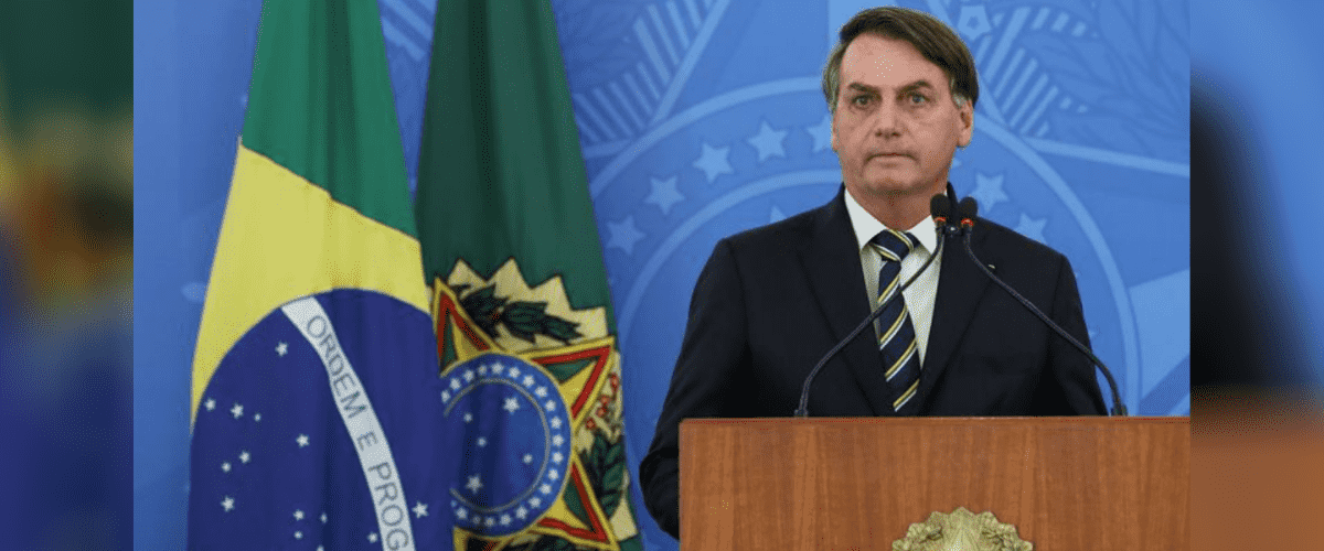 Conheça a lei de negociação de dívidas das micro empresas: Jair Bolsonaro aparece em púlpito à frente de fundo azul com o brasão Federal