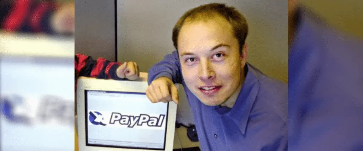 Elon Musk aparece apoiado em computador com logo do PayPal como fundo de tela