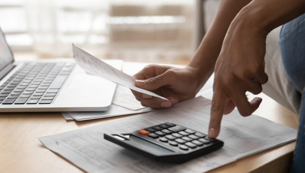 homem realiza cálculos na calculadora a partir de uma planilha