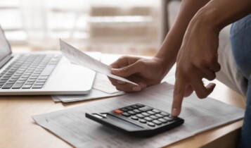 homem realiza cálculos na calculadora a partir de uma planilha