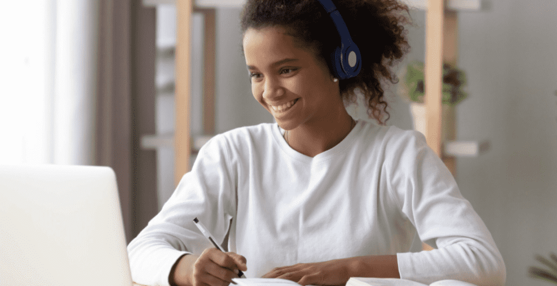 Foto mostra mulher sentada em frente ao computador e sorrindo para aprender inglês grátis