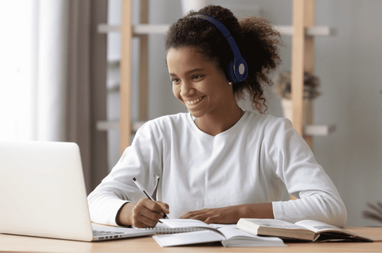 Foto mostra mulher sentada em frente ao computador e sorrindo para aprender inglês grátis