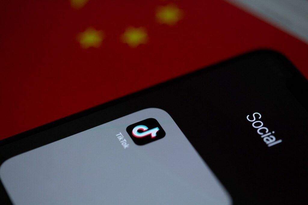 O TikTok é seguro? Celular com logo do TikTok apoiado em bandeira da china