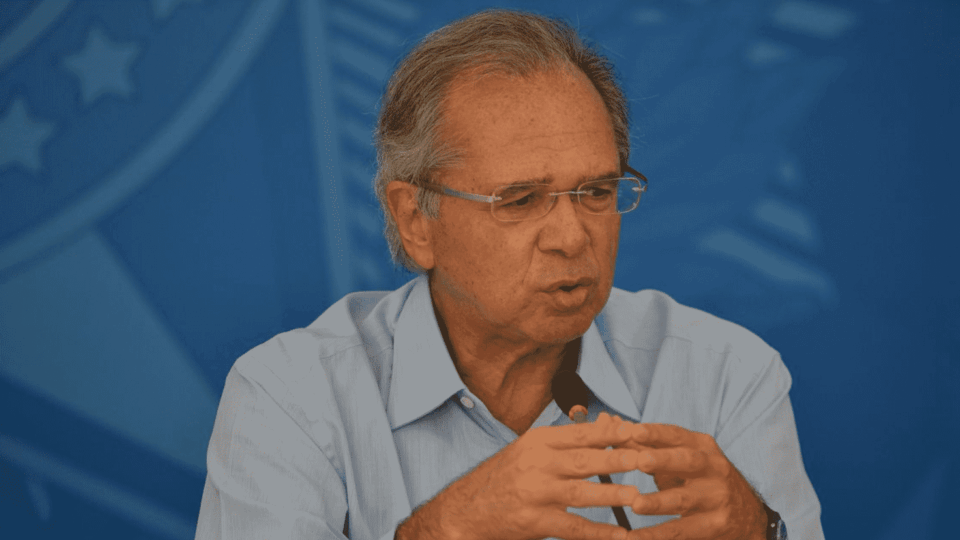 Foto mostra Paulo Guedes falando em um microfone. imposto digital
