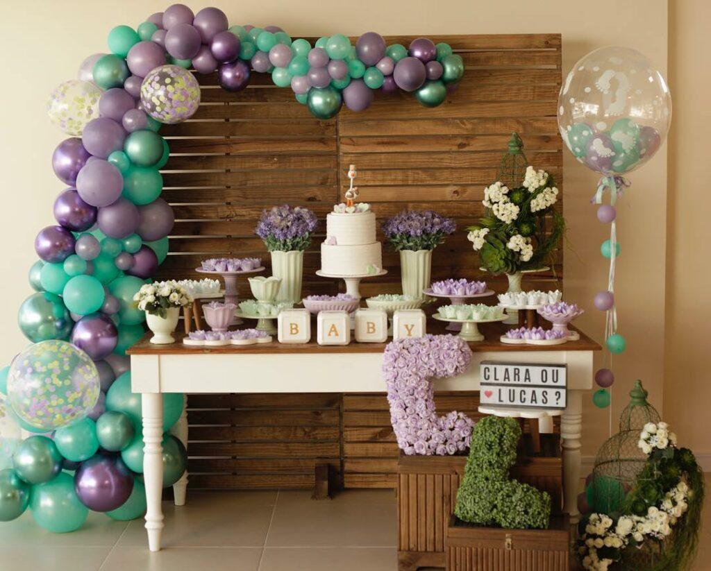 Decoração com mesa de bolo e balões lilás e verde para chá revelação