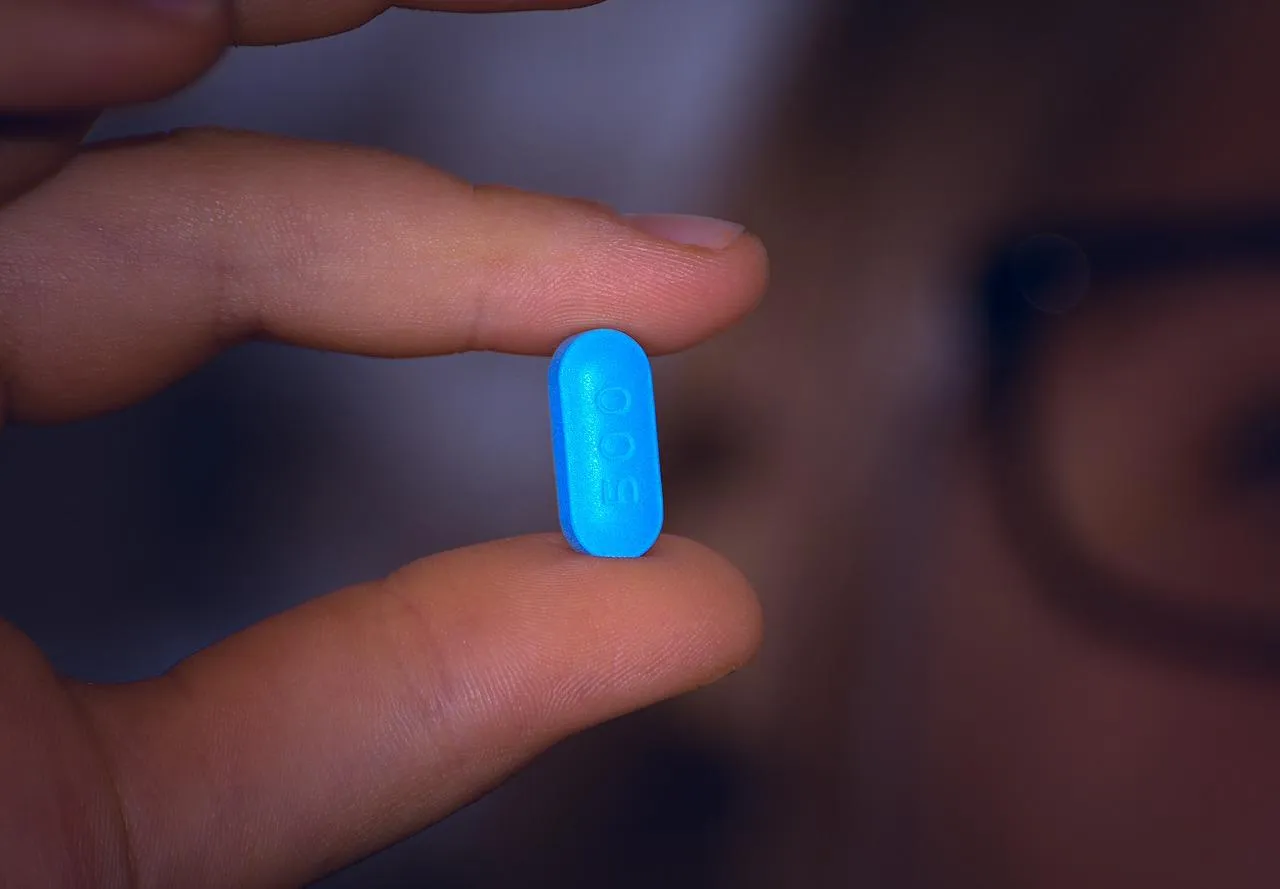 dedos polegar e indicador segunda uma pílula azul. 
