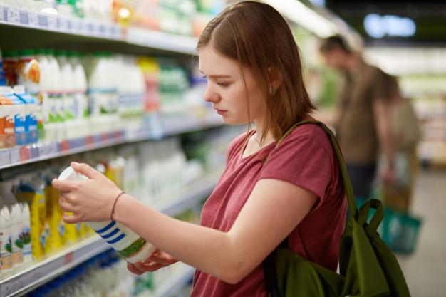 Foto de modelo atraente jovem consumidor feminino com penteado cortado vestido com camiseta casual fica em uma grande loja segura a garrafa de leite 176532 1228