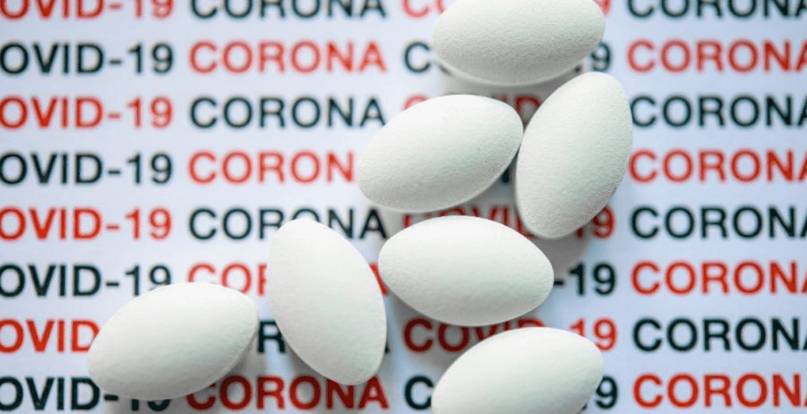 Imagem mostra comprimidos brancos em cima de um fundo com a palavra "COVID-19" escrita várias vezes.