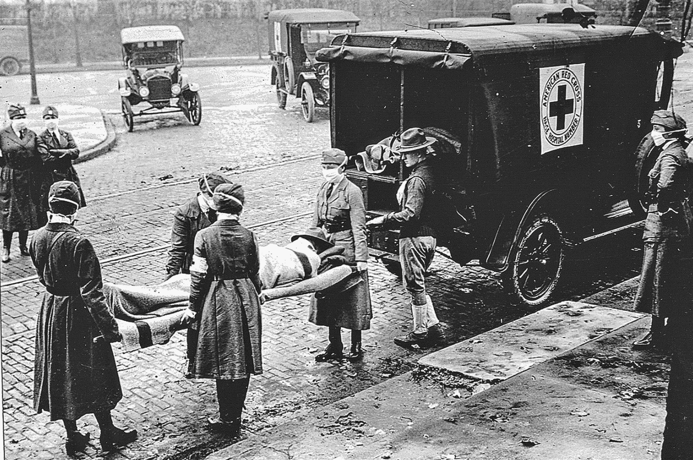 Foto antiga mostra soldados carregando outro soldado em uma maca para o colocar em uma ambulância.