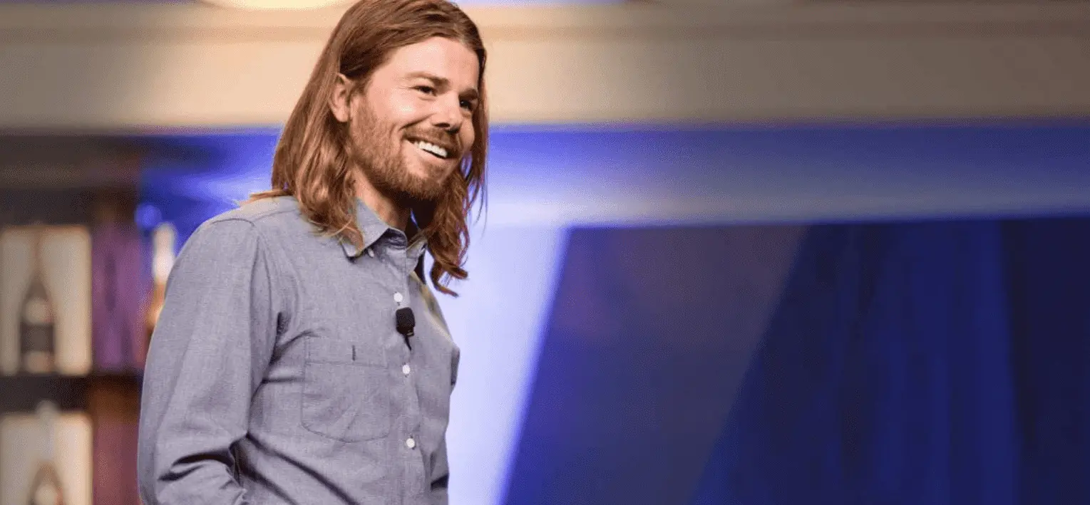 Foto mostra Dan Price, posição 3/4, da cintura para cima, usad