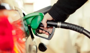 Uma mão coloca a pistola de gasolina no tanque para reabastecer o carro.