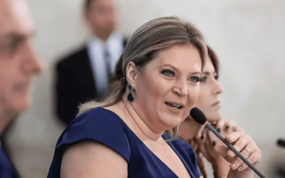 Foto mostra Joice Hasselman falando ao microfone, de lado.