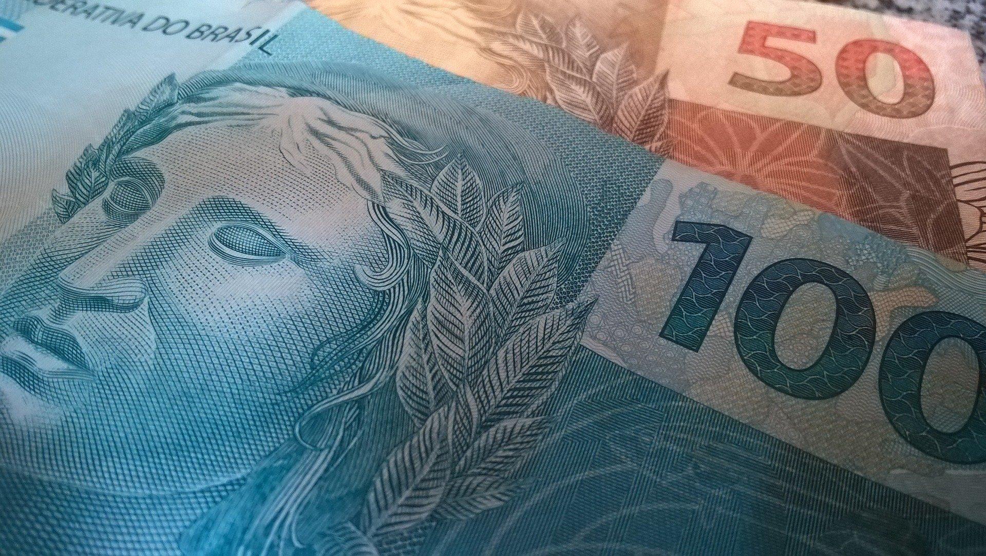 Cédula de 100 reais sobre outra cédula de 50 reais