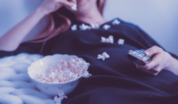 Mulher comendo pipoca e assistindo uma série premiada pela Prime Video