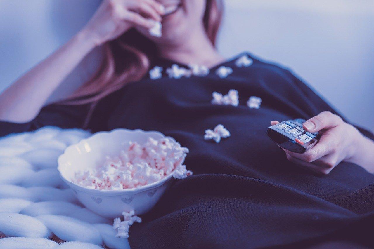 Mulher comendo pipoca e assistindo uma série premiada pela Prime Video