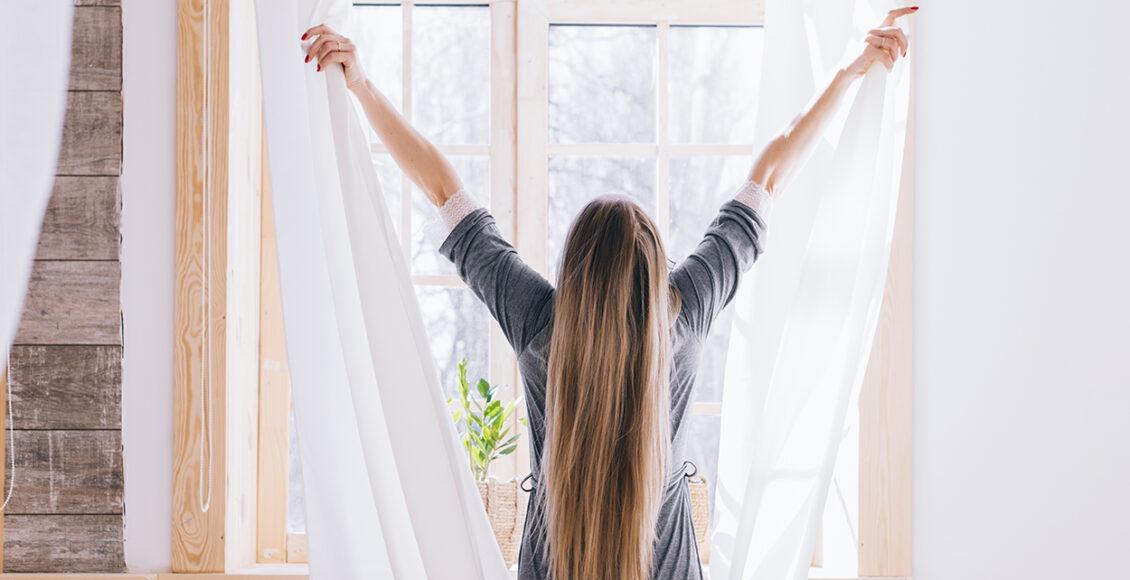 Como refrescar o quarto: Imagem de mulher abrindo cortinas