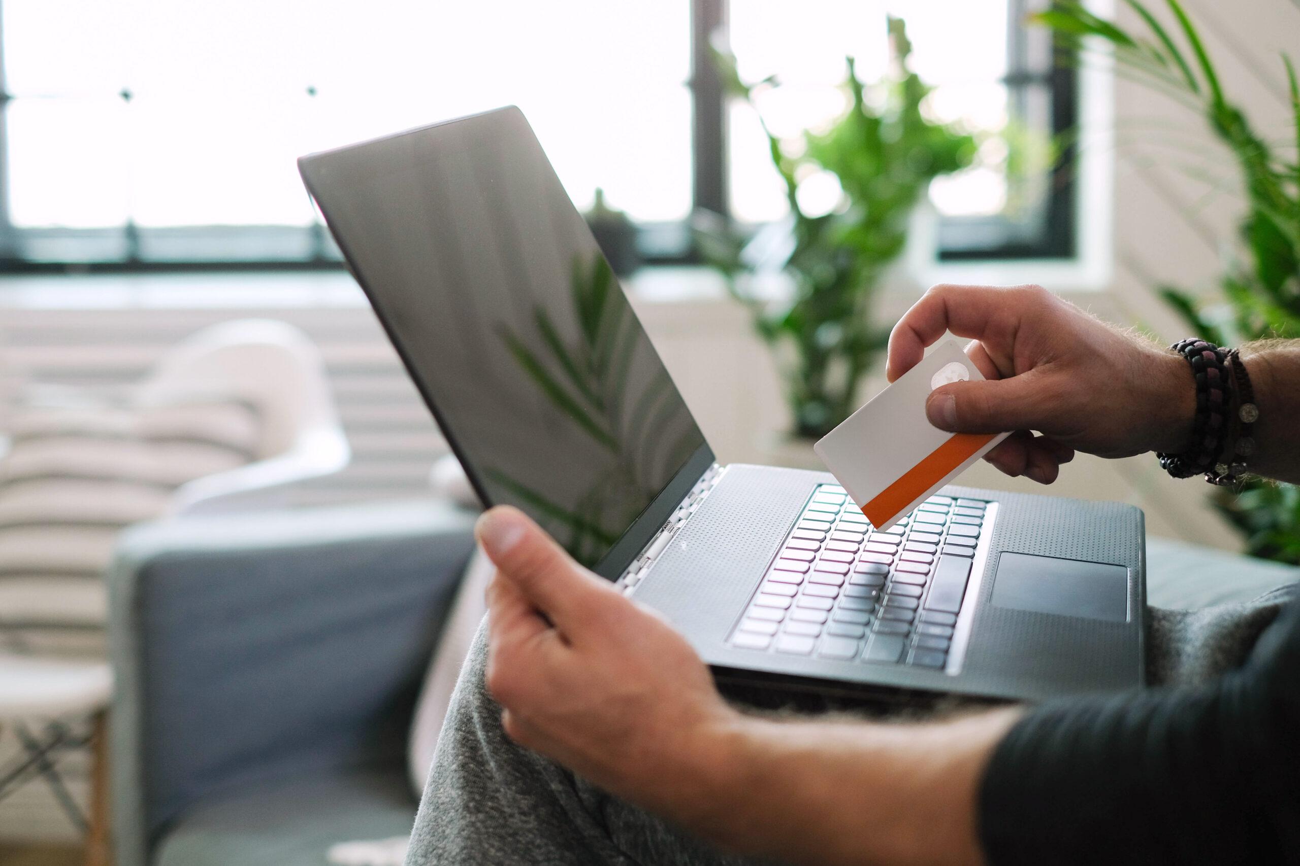 Homem usando notebook com cartão de crédito na mão. Homem usando notebook com cartão de crédito na mão.