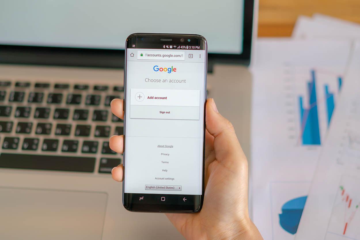 Homem segurando celular com conta Google