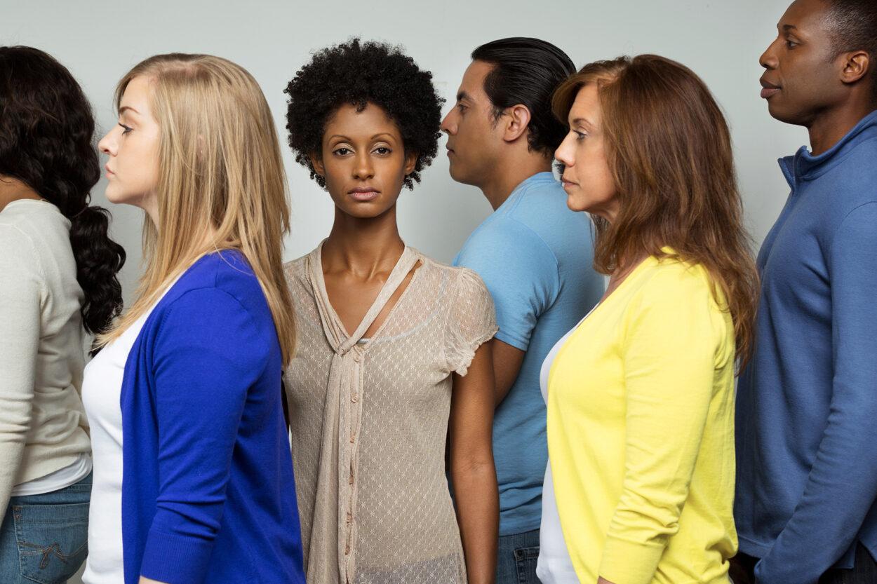 mulher negra de frente enquanto brancos e homens estão de perfil