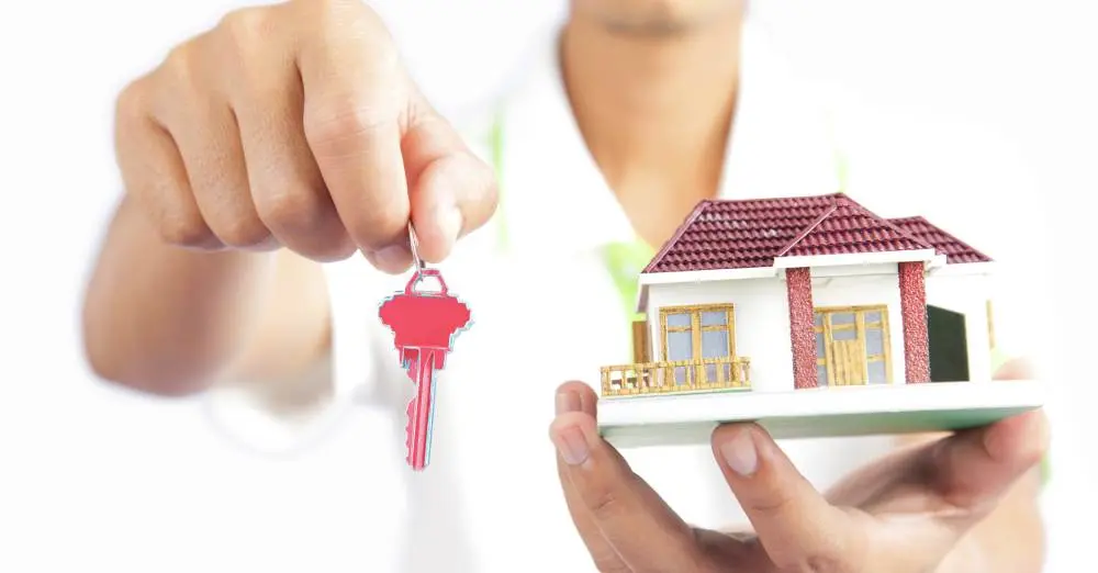 pessoa segurando chave e miniatura de casa